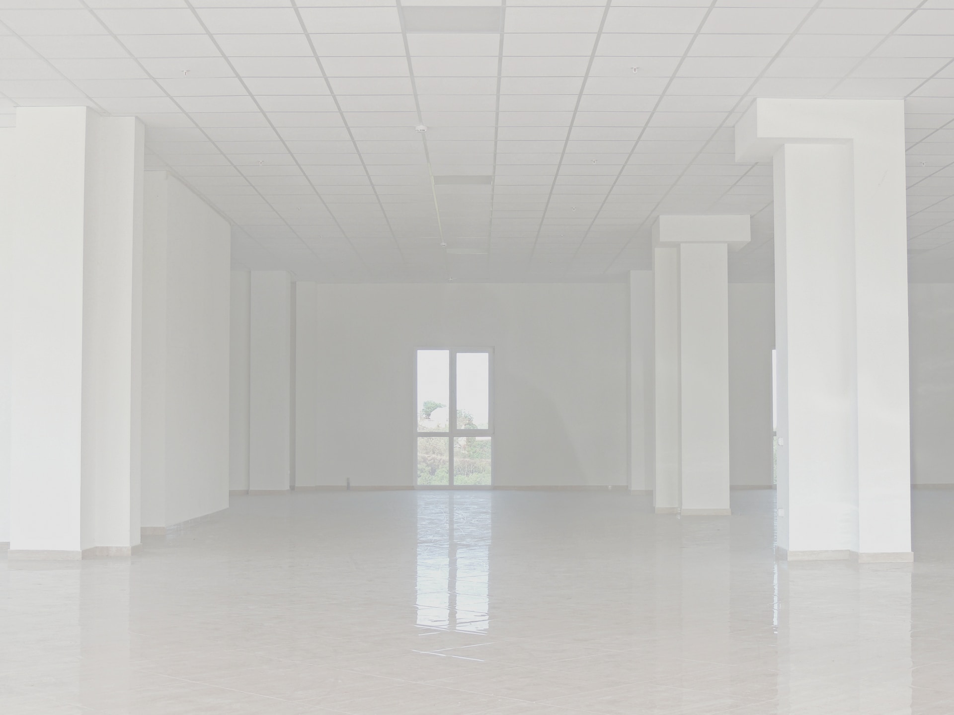 A faded image of empty floors and white walls. A two pane window is directly across the room from the viewer.